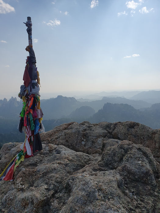 A pole with fabric on top of a mountain Description automatically generated