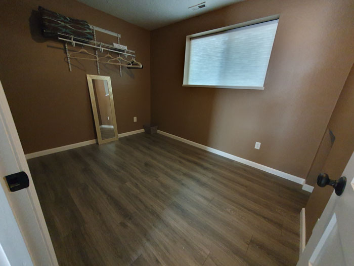 A room with a mirror and a wood floor Description automatically generated