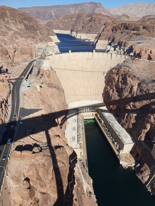 A large dam with a body of water with Hoover Dam in the background Description automatically generated