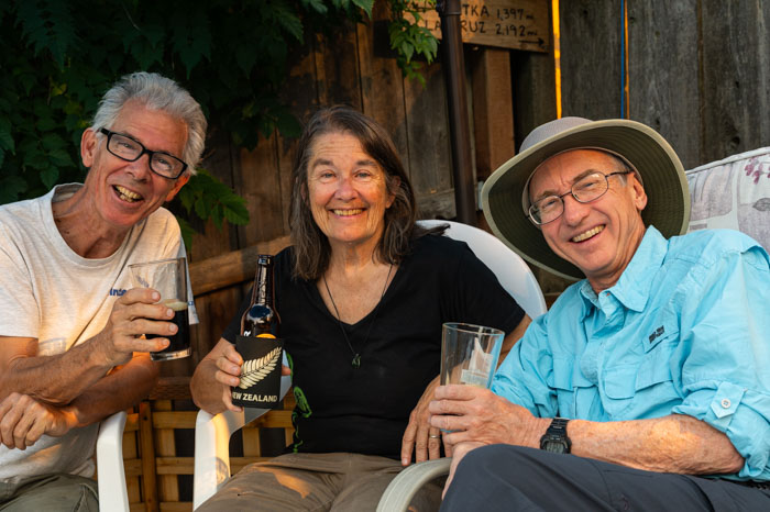 A group of people sitting in a chair holding drinks and a bottle Description automatically generated